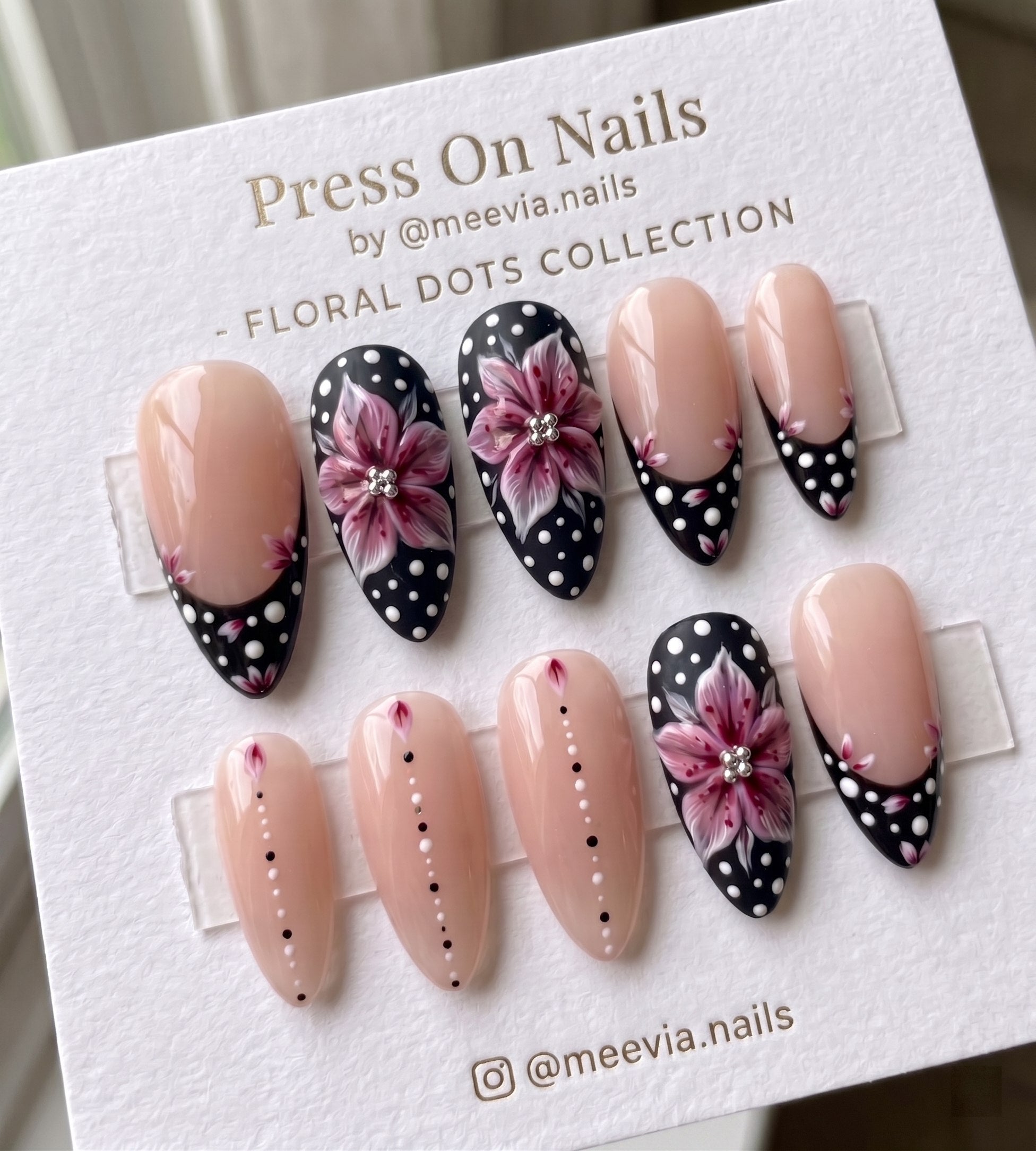 Almond-shaped press on nails with pink floral art and black dotted French tips