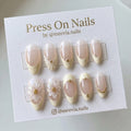Almond-shaped floral French tip press-on nails with 3D flower art and gold bead accents