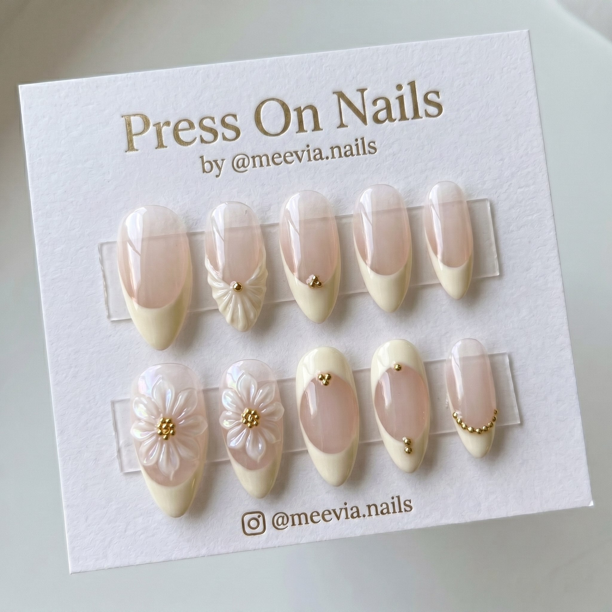Almond-shaped floral French tip press-on nails with 3D flower art and gold bead accents