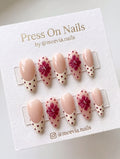 Almond-shaped floral French tip press-on nails with 3D accents and polka dots
