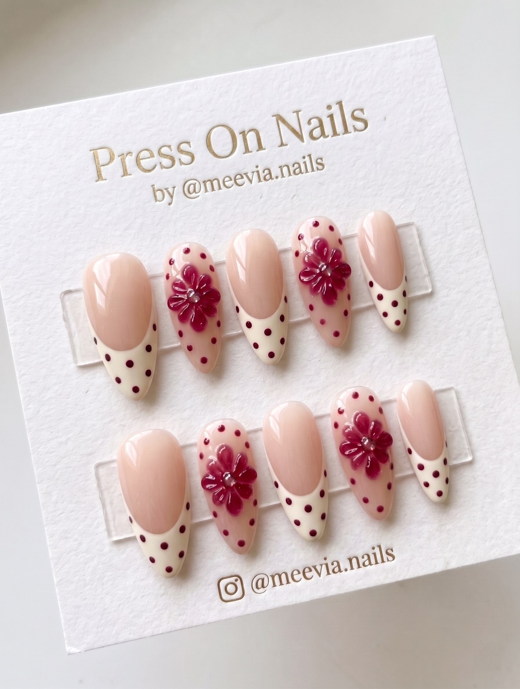 Almond-shaped floral French tip press-on nails with 3D accents and polka dots