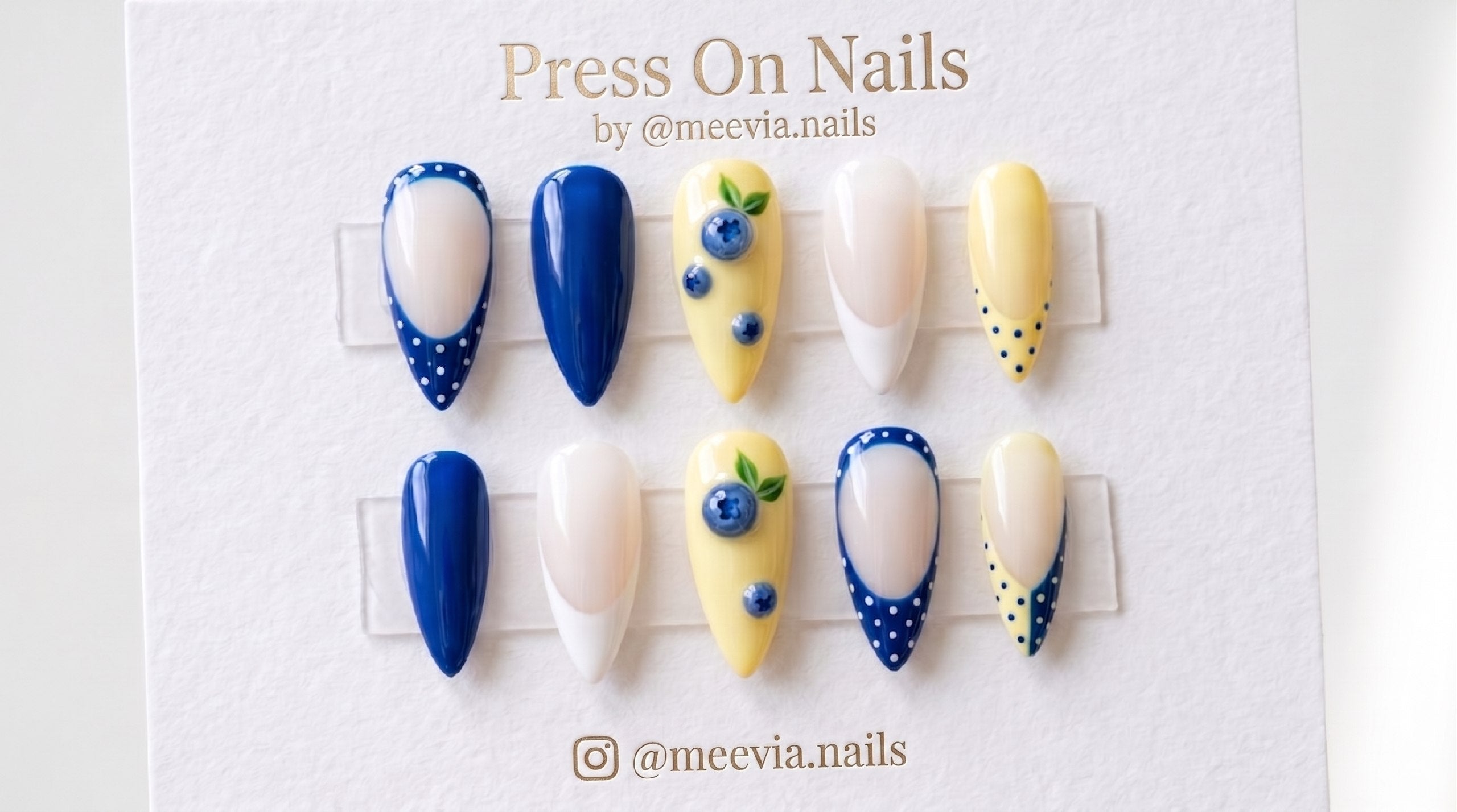 Almond-shaped press-on nail set featuring 3D blueberries, butter yellow base, and blue polka dots.