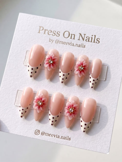 Almond-shaped press on nails featuring pink 3D floral art and polka dot French tips