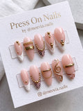 Almond-shaped nude press-on nails with gold 3D accents and white French tips