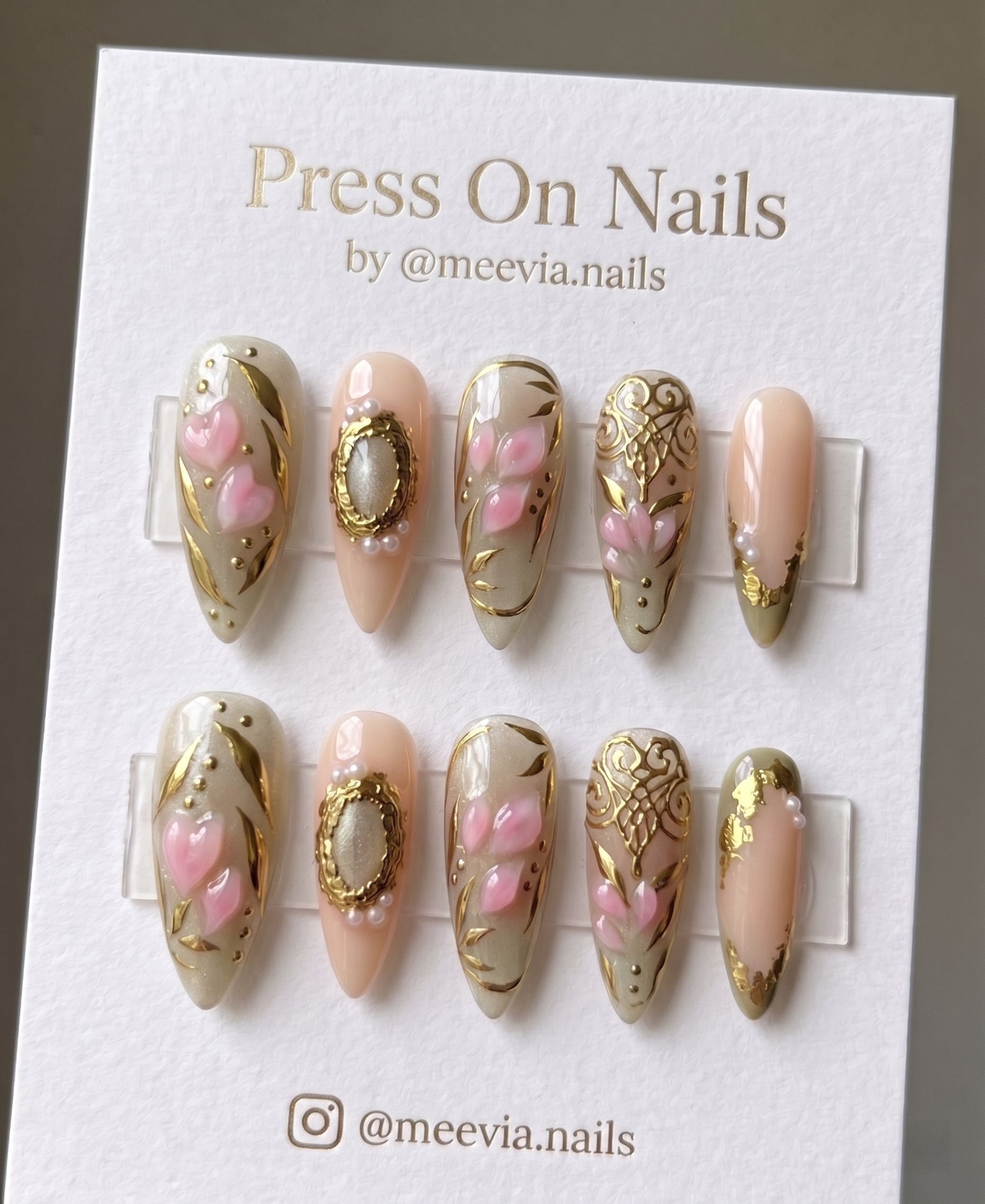 Almond-shaped nude press on nails with 3D pink hearts and gold filigree accents