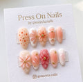 Almond-shaped floral press-on nails featuring 3D flower petals and gold bead accents