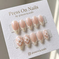 Almond-shaped shimmer French tip press-on nail set with 3D white flowers and gold accents