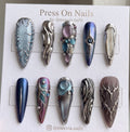 Stiletto-shaped metallic press-on nails with 3D chrome details and celestial motifs