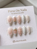 Almond-shaped white and nude press-on nail set with pearls and black polka dots