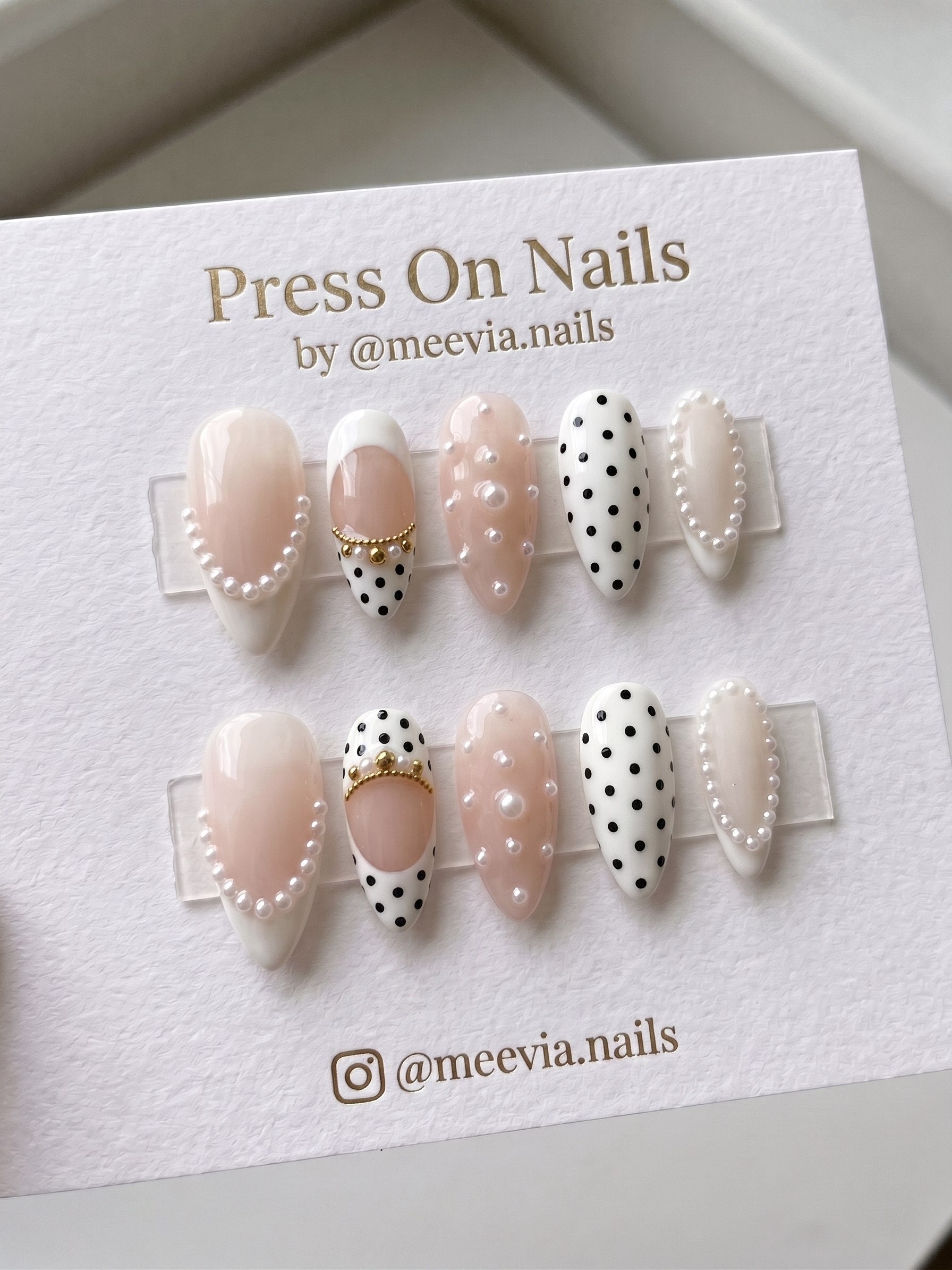 Almond-shaped white and nude press-on nail set with pearls and black polka dots