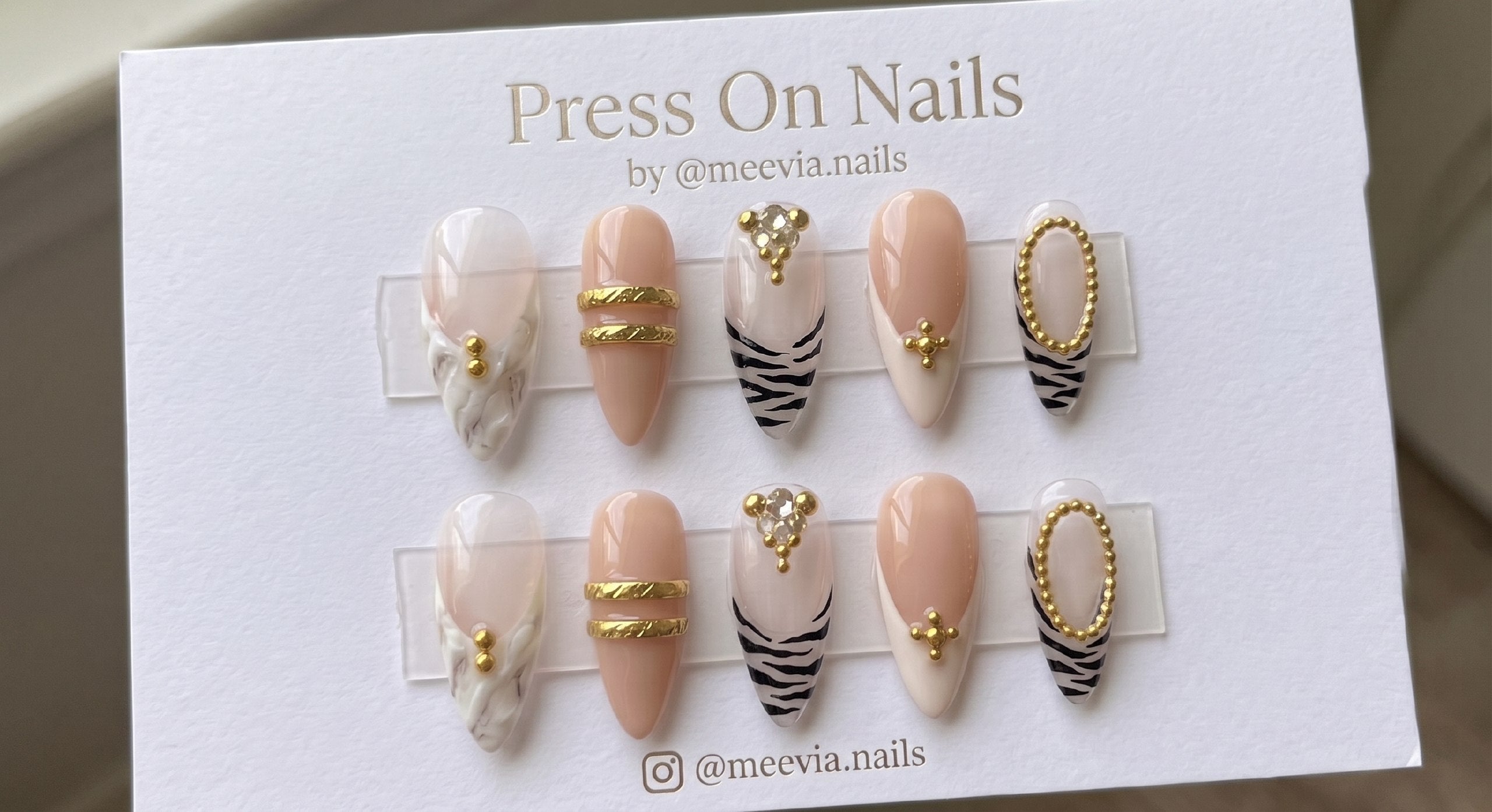 Almond-shaped zebra print press-on nails with gold accents and 3D nail art