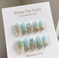 Almond-shaped light blue and white press-on nail set with 3D gold hearts and floral art