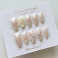 Almond-shaped glazed press-on nails featuring 3D shell and floral designs with crystal accents.