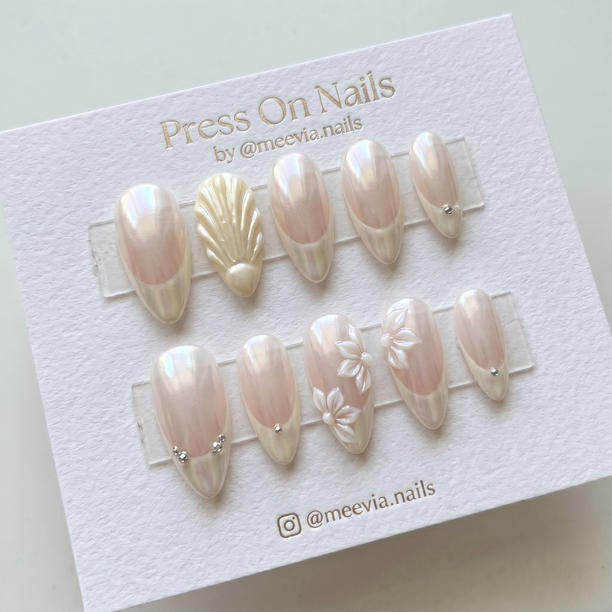 Almond-shaped glazed press-on nails featuring 3D shell and floral designs with crystal accents.