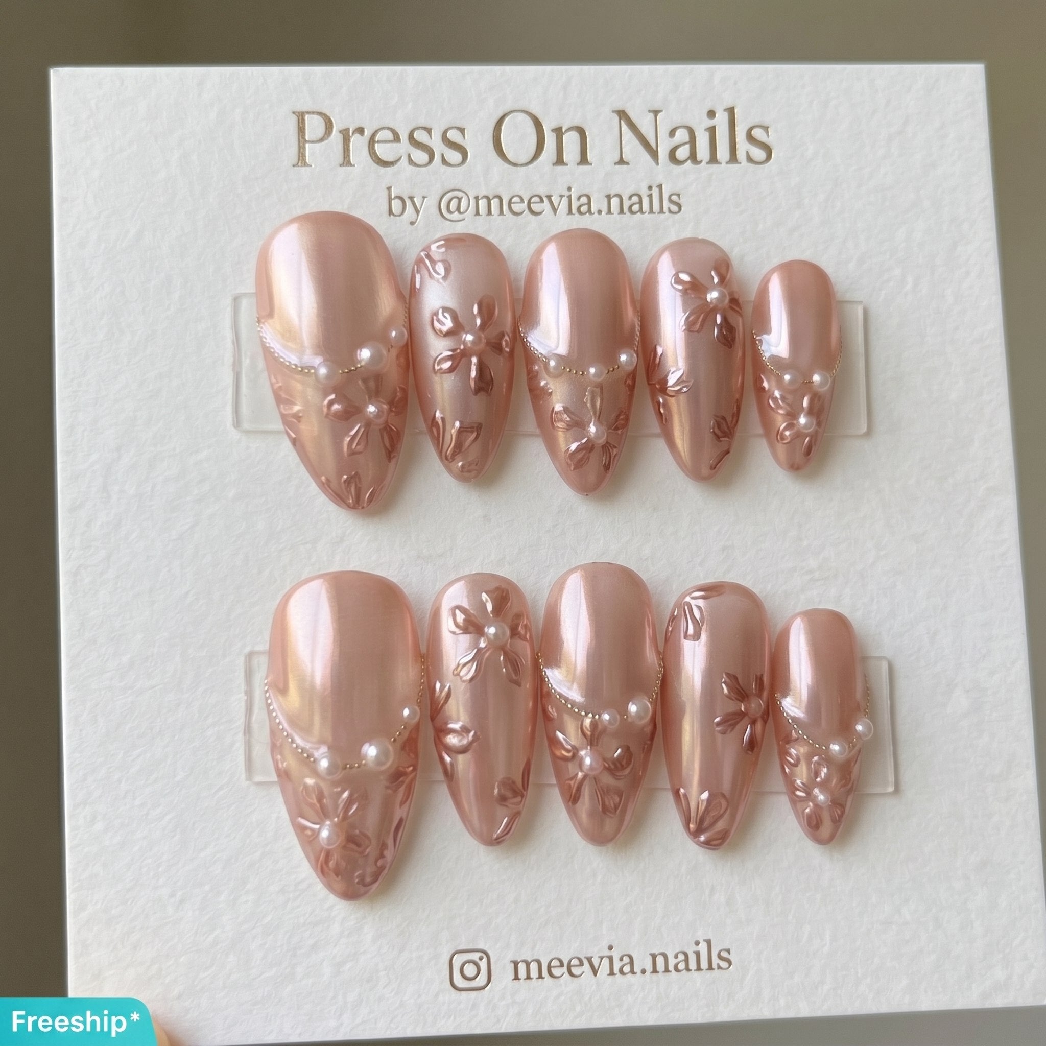 Almond-shaped pink chrome press-on nails with 3D floral art and pearl embellishments