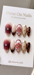 Almond-shaped press on nails featuring 3D floral art, tortoise shell patterns, and gold celestial accents.