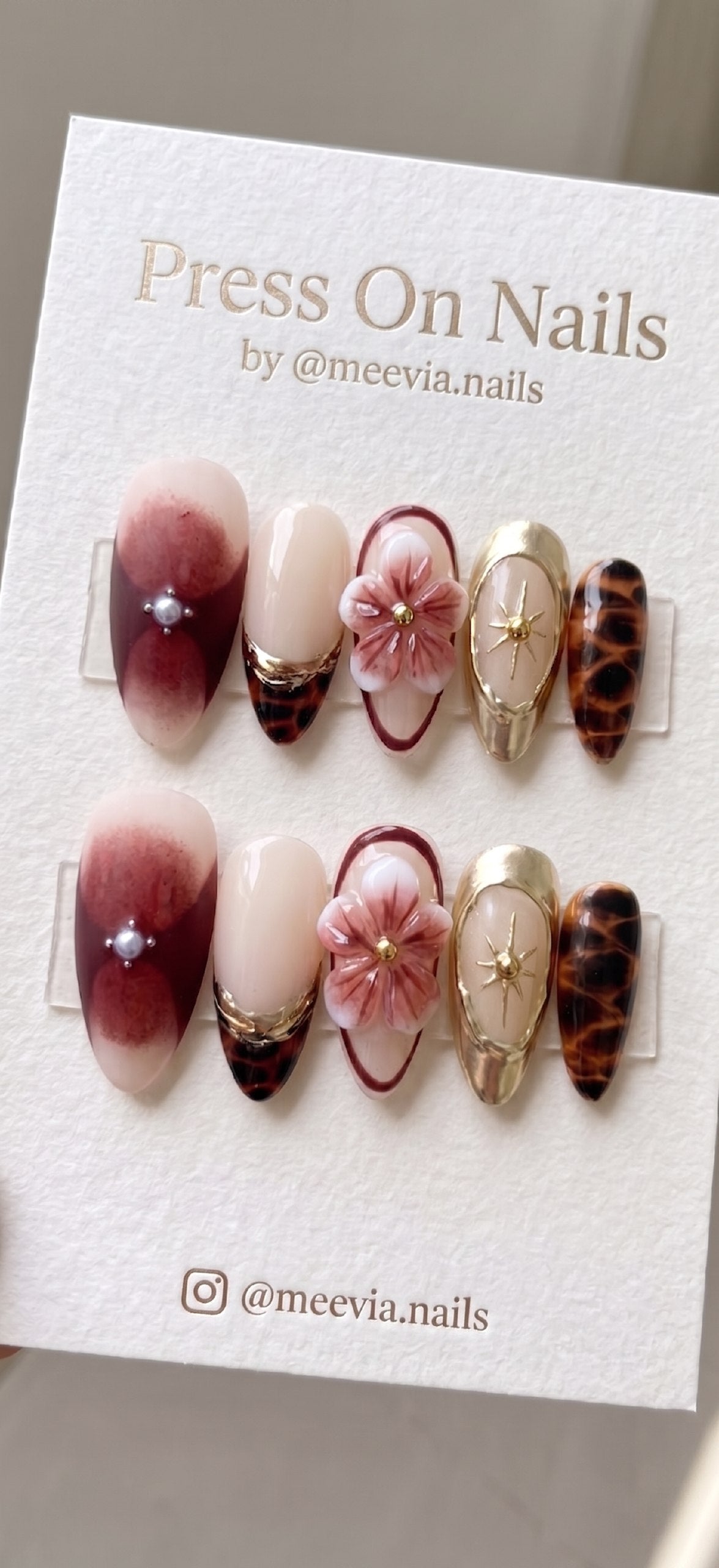 Almond-shaped press on nails featuring 3D floral art, tortoise shell patterns, and gold celestial accents.