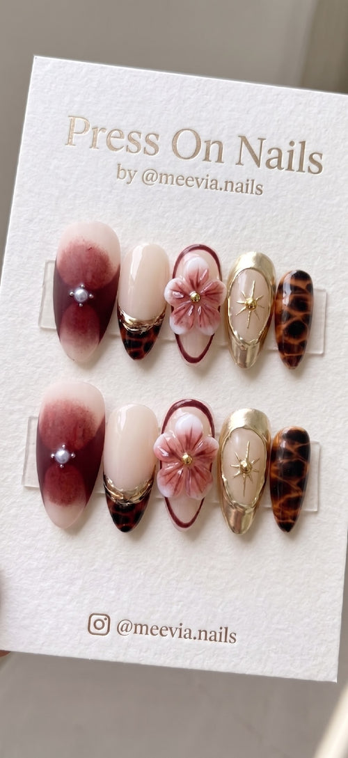 Almond-shaped press on nails featuring 3D floral art, tortoise shell patterns, and gold celestial accents.