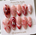 Almond-shaped red floral press-on nails with 3D art and metallic accents.