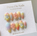 Almond-shaped pastel gradient press-on nails with 3D floral art and dewdrop details