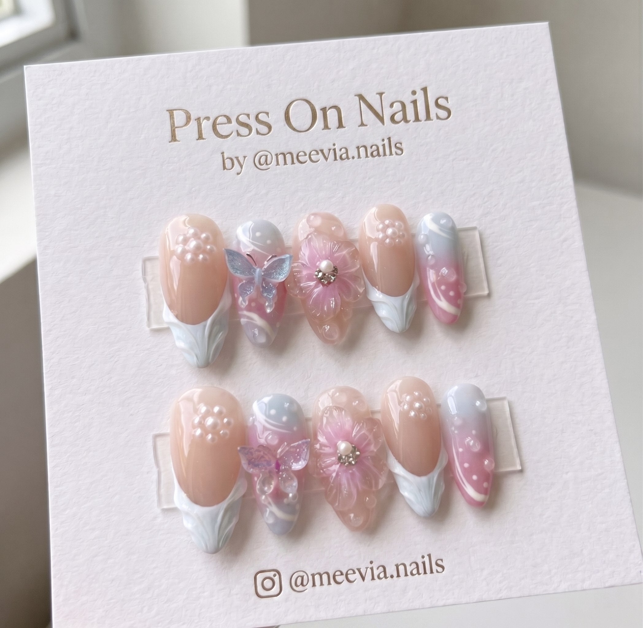 Almond-shaped pink floral butterfly press-on nails with 3D accents and French tips.