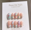 Square-shaped floral press-on nails with glitter accents and a clear finish