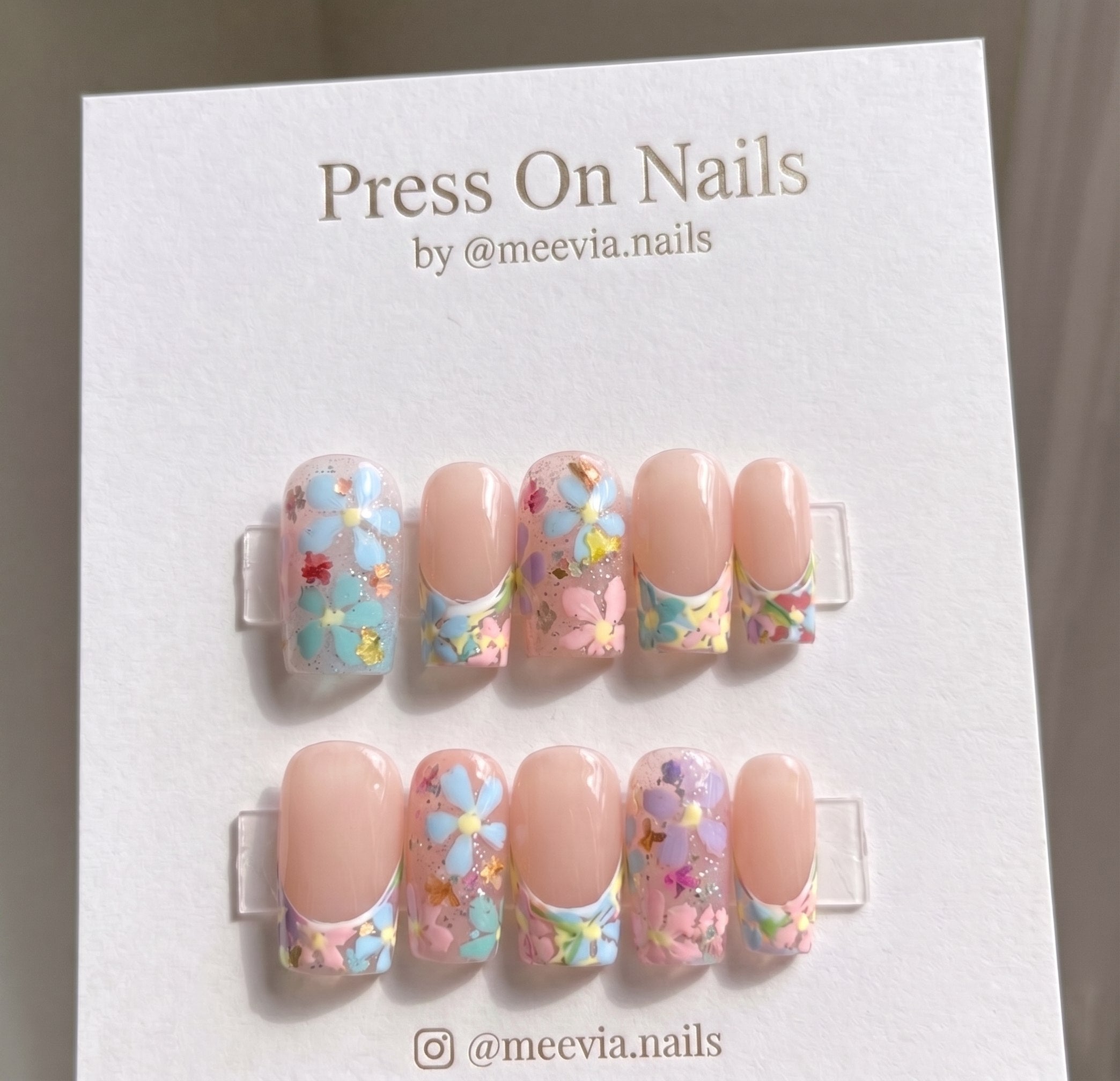 Square-shaped floral press-on nails with glitter accents and a clear finish