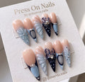 Long stiletto press-on nail set with 3D shell textures, navy floral motifs, and pearl accents.