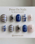 Short oval celestial press-on nail set with 3D silver accents, blue star motifs, and iridescent finishes