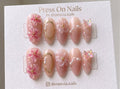 Almond-shaped floral and butterfly press-on nails with 3D nail art and pink jelly finish