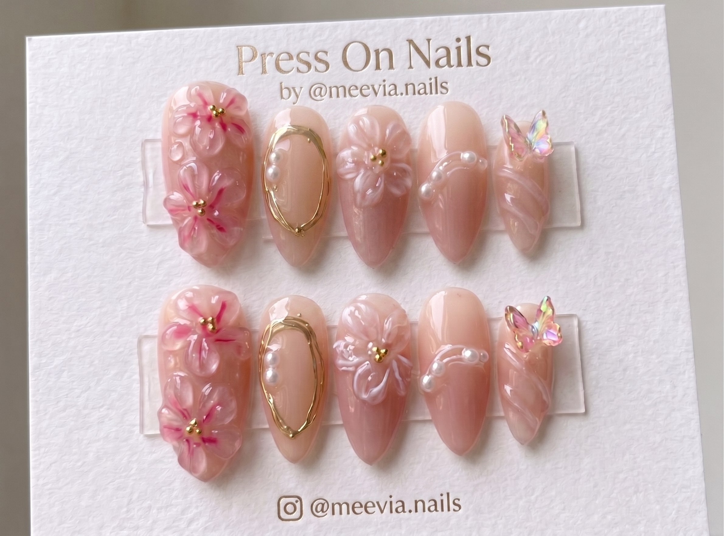Almond-shaped floral and butterfly press-on nails with 3D nail art and pink jelly finish