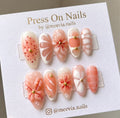 Almond-shaped peach and white press-on nail set with 3D floral designs and gold studs