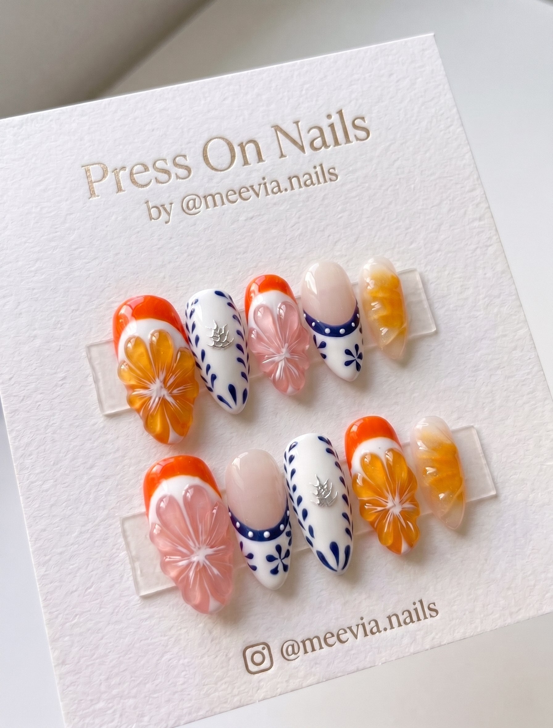 Almond-shaped press-on nails featuring 3D citrus fruit and blue floral art