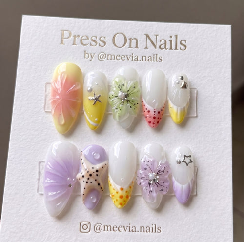 Almond-shaped press-on nail set with 3D ocean shells, starfish, and floral motifs in pastel colors.