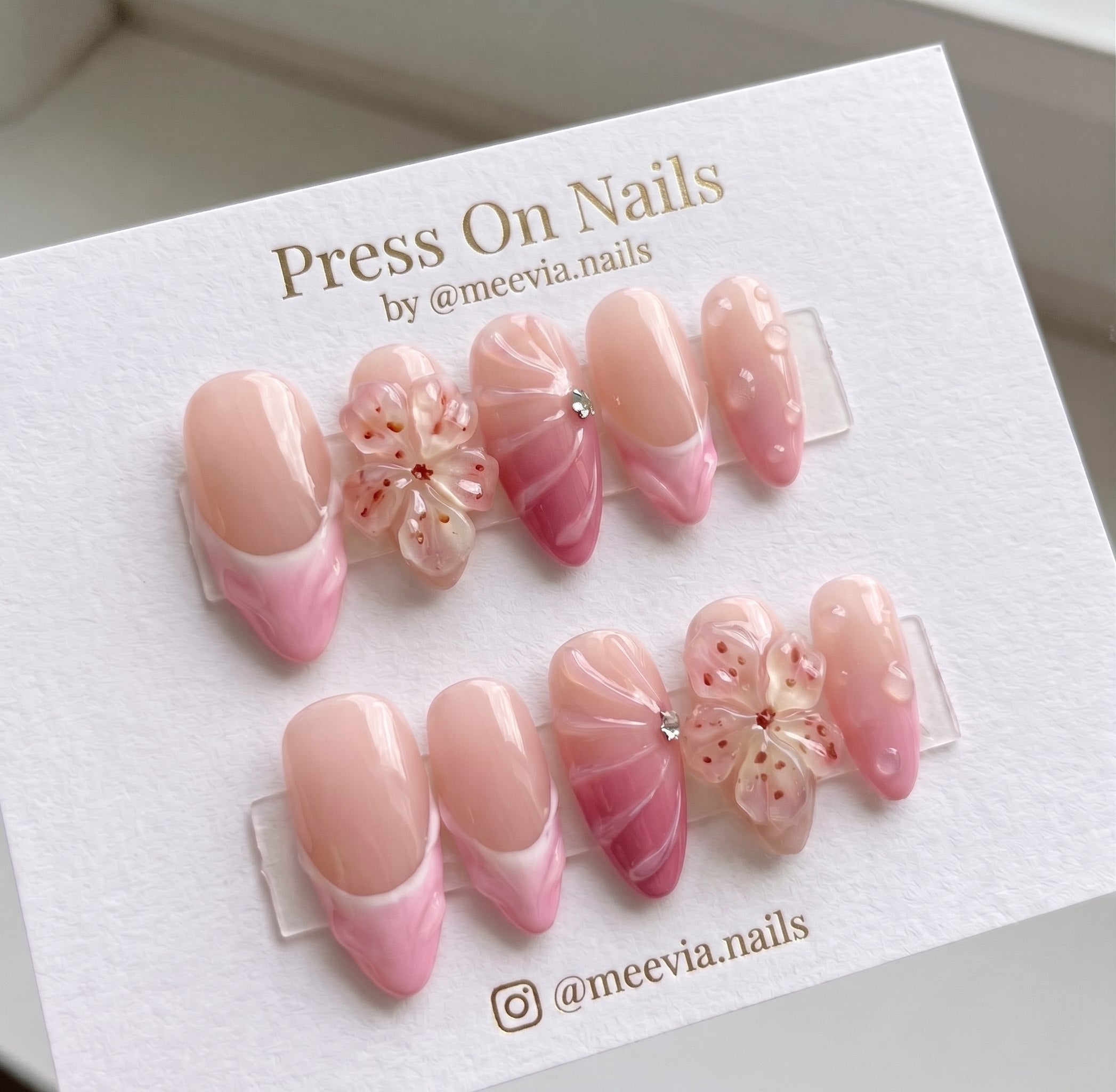Almond-shaped pink press-on nail set with 3D sakura flowers and water drop nail art