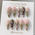 Stiletto-shaped pink and green press-on nails with 3D flowers and metallic butterfly art