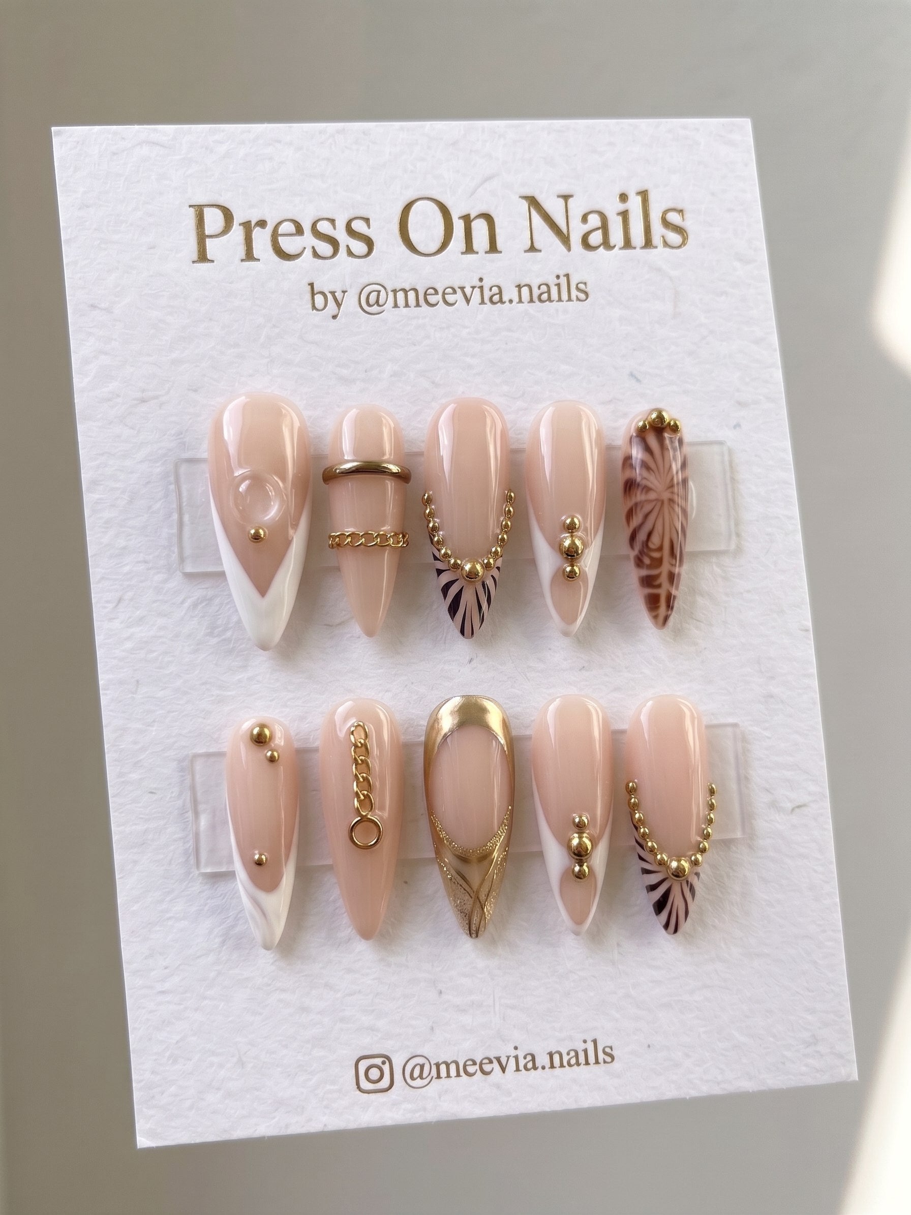Stiletto shaped nude press-on nails with gold chains and animal print accents