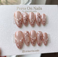 Almond shaped pearlescent pink press-on nails with 3D rose gold floral art and white pearls.