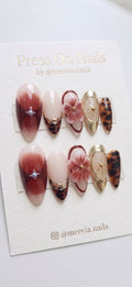 Almond-shaped burgundy and gold press-on nail set with 3D floral art and tortoiseshell patterns