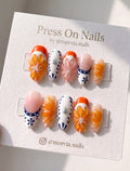Almond-shaped orange citrus 3D press-on nails with blue and white porcelain accents