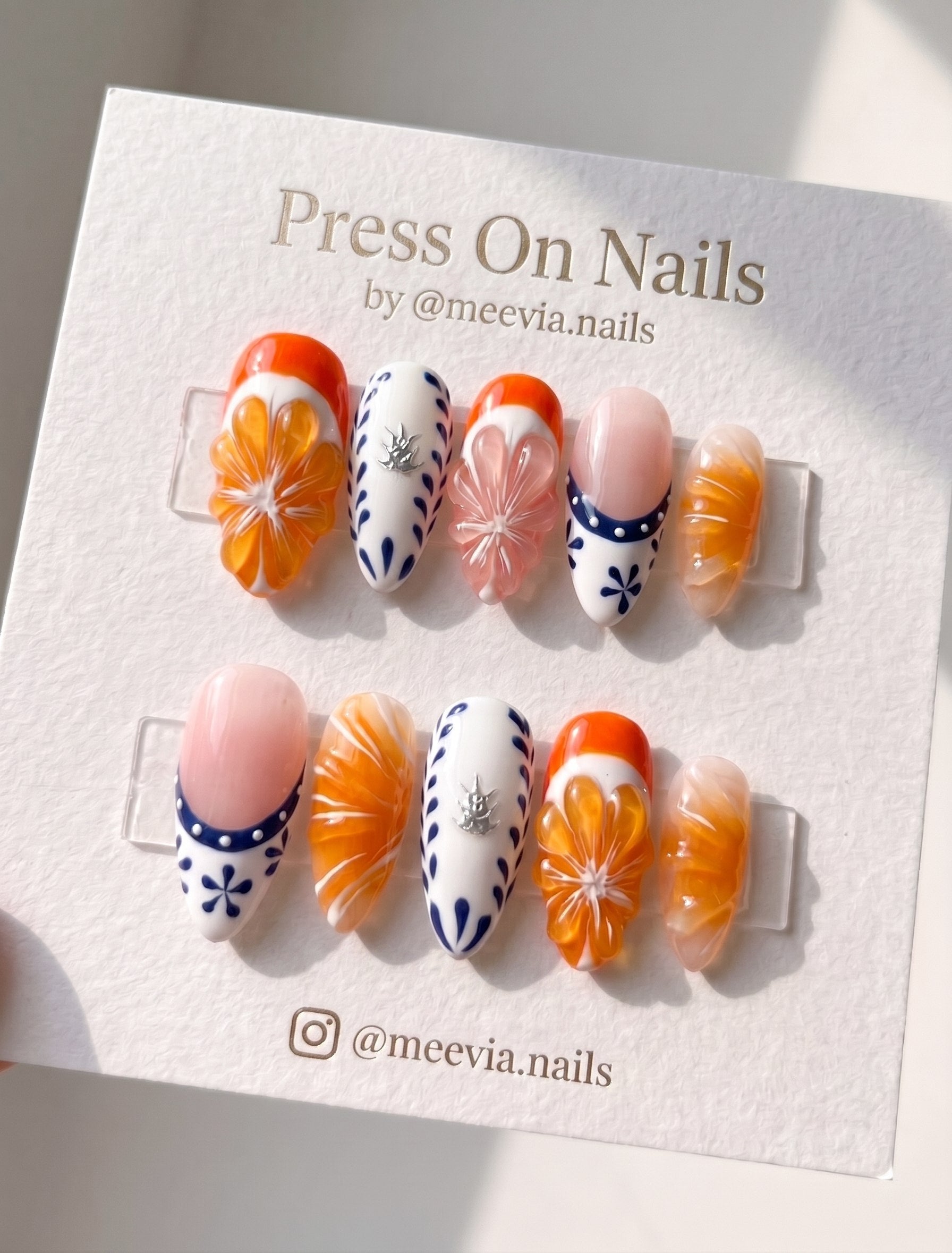 Almond-shaped orange citrus 3D press-on nails with blue and white porcelain accents
