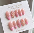 Almond-shaped pink press-on nails featuring 3D floral designs and subtle gems.