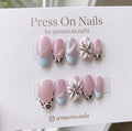 Almond-shaped pink shimmer press-on nails with 3D floral art, leopard print, and light blue French tips.