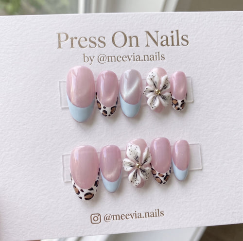 Almond-shaped pink shimmer press-on nails with 3D floral art, leopard print, and light blue French tips.