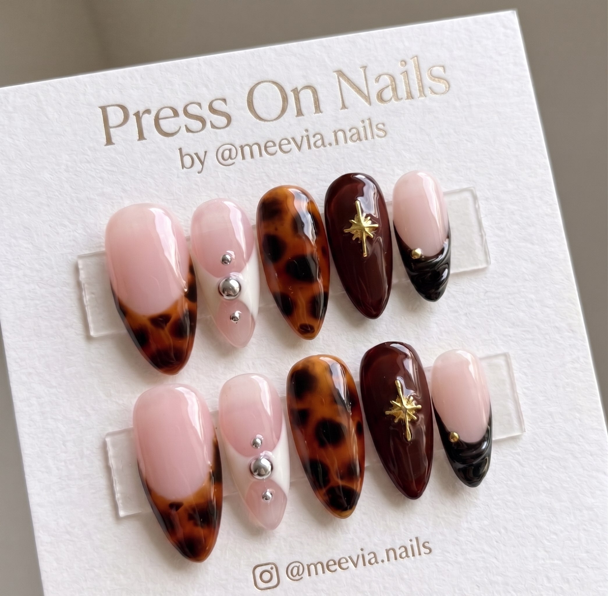 Almond-shaped tortoiseshell press-on nails featuring gold star accents and French tips