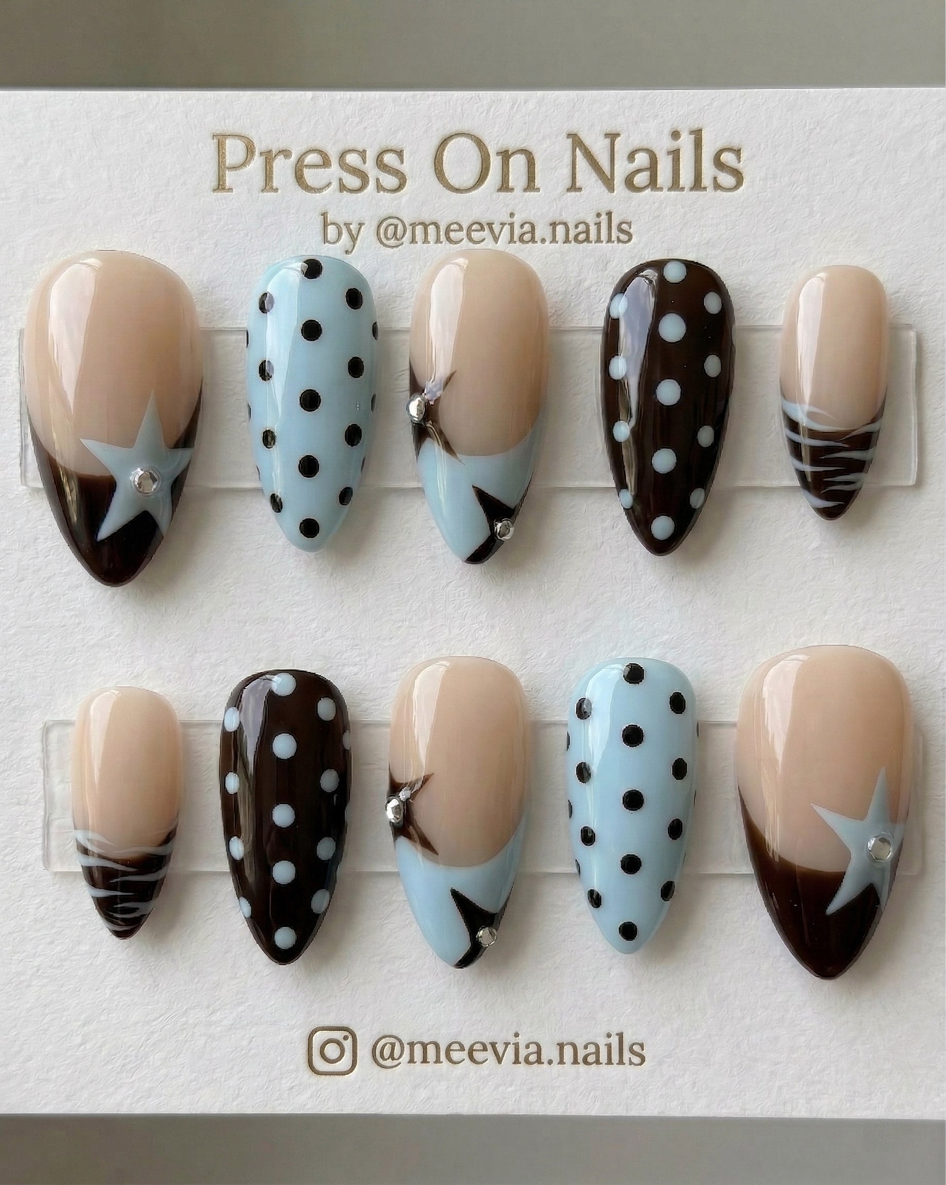 Almond-shaped press-on nail set with blue and brown star and polka dot motifs