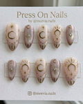 Almond-shaped celestial press-on nail set with gold moon and star motifs and shimmer finish