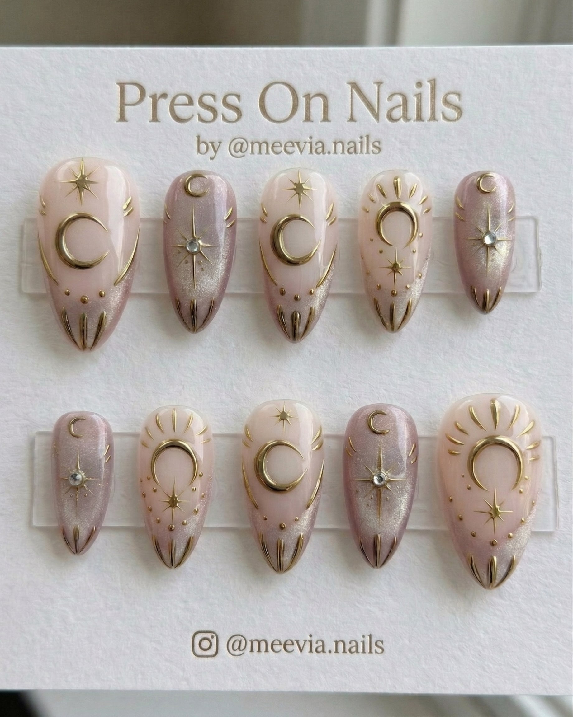 Almond-shaped celestial press-on nail set with gold moon and star motifs and shimmer finish