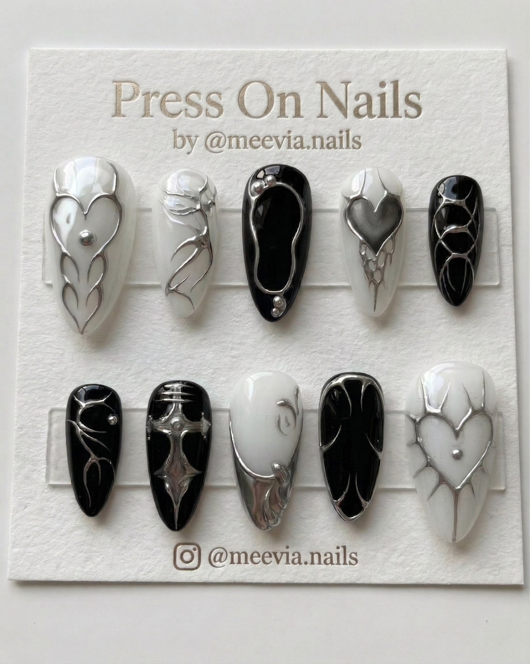 Stiletto-shaped black and white press-on nail set with 3D silver chrome heart and gothic motifs