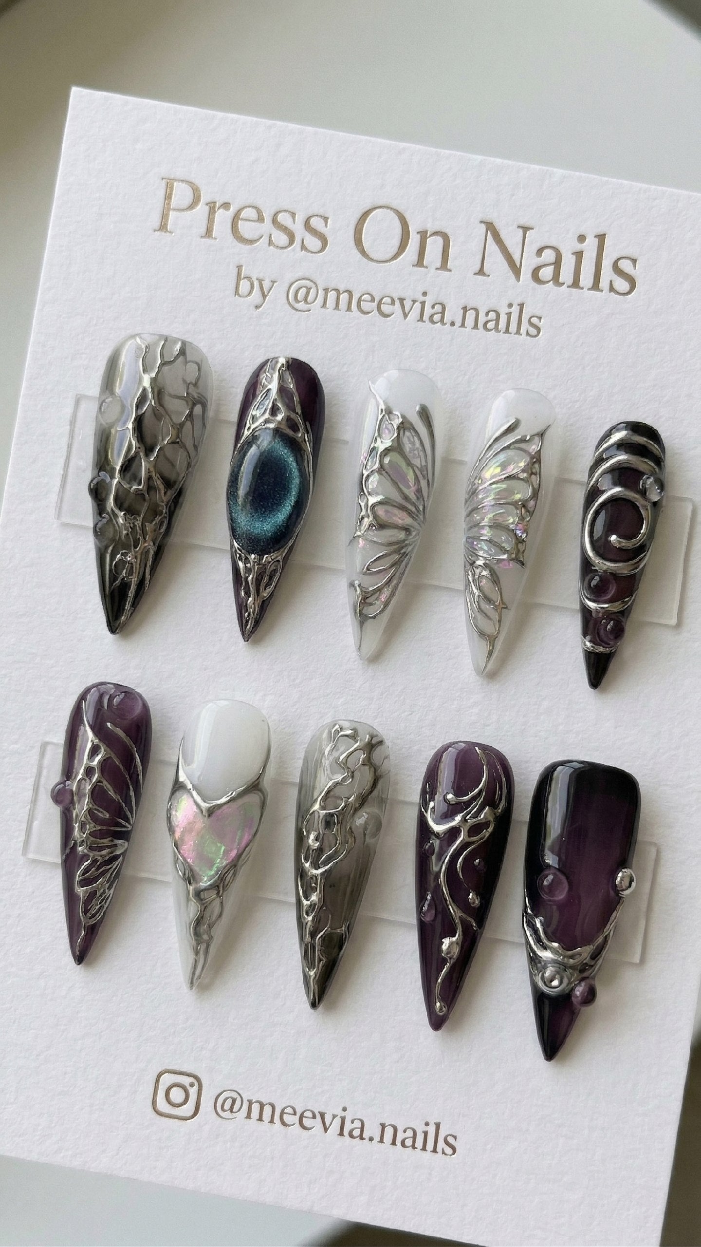 Long stiletto press on nails with purple jelly base, 3D silver chrome swirls, and iridescent butterfly wing motifs.